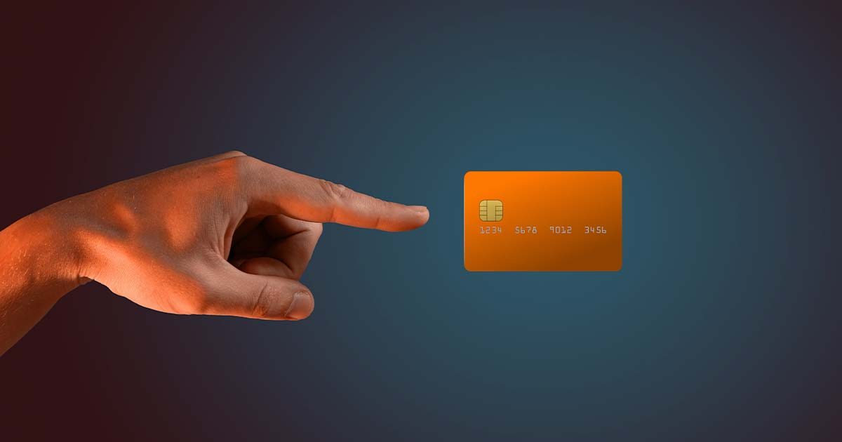 يد تشير نحو بطاقة دفع إلكترونية بلون برتقالي على خلفية داكنة للدلالة على خدمات الدفع السريعة والآمنة