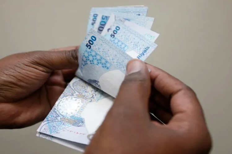 صورة تظهر يدا رجل بصدد عدّ أوراق نقدية من فئة 500 ريال قطري