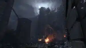 A dark, atmospheric screenshot of a ruined stone castle under a moonlit sky with a small fire in the foreground.