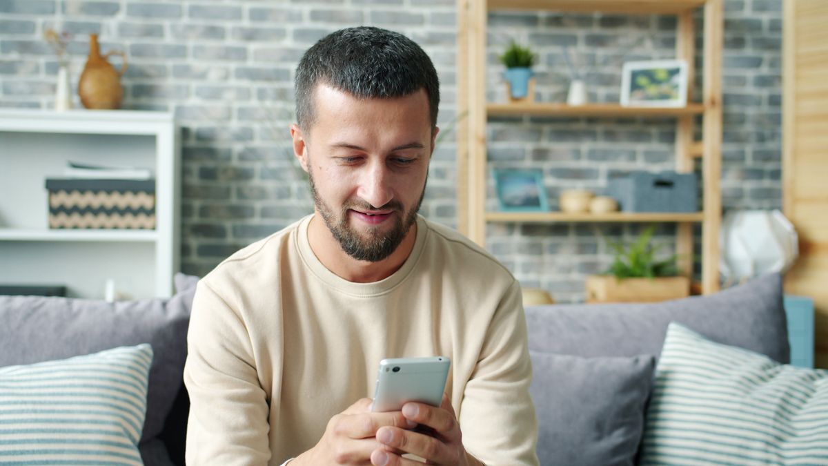 Man using a smartphone on a sofa at home, the typical way players use a mobile casino app