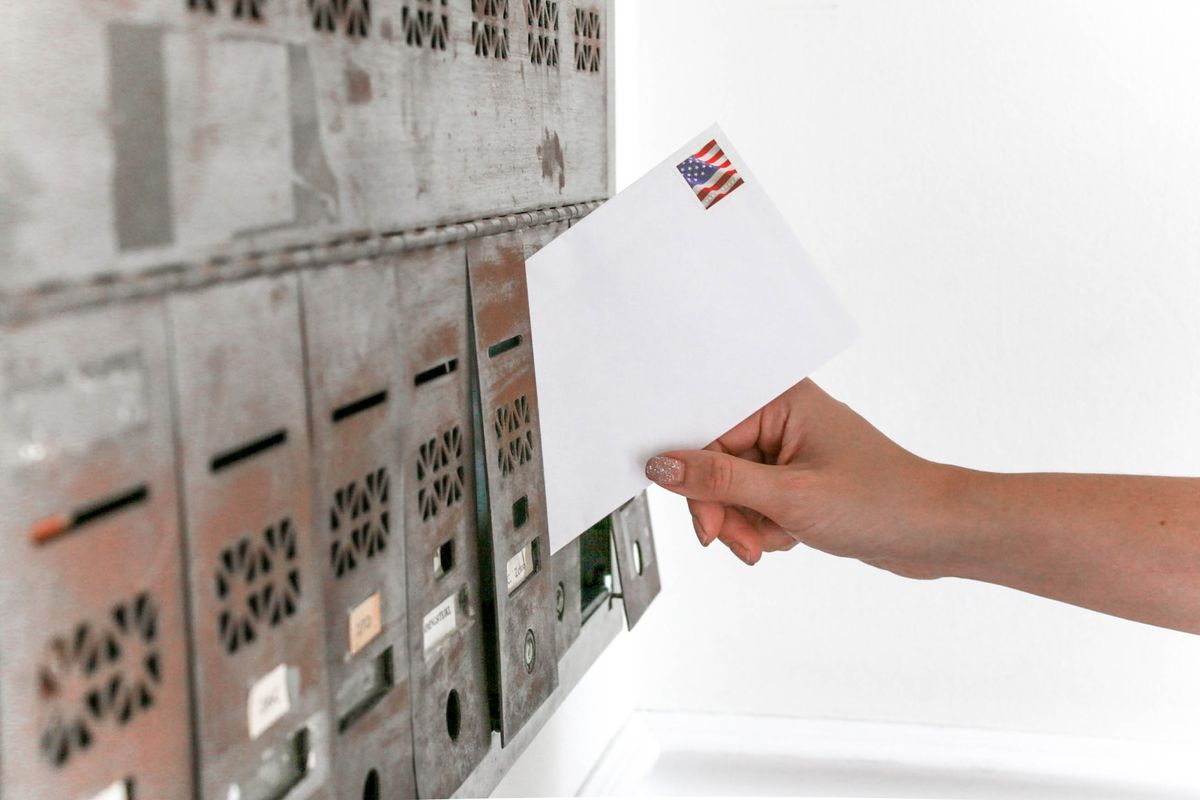 Hand posting a stamped envelope into a mailbox, the free mail-in route to Sweeps Coins