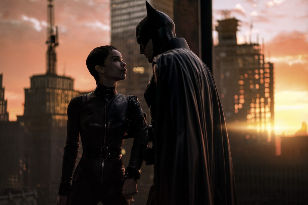 Catwoman (Zoe Kravitz) faces Batman (RobertPattinson - a masked man against a city backdrop
