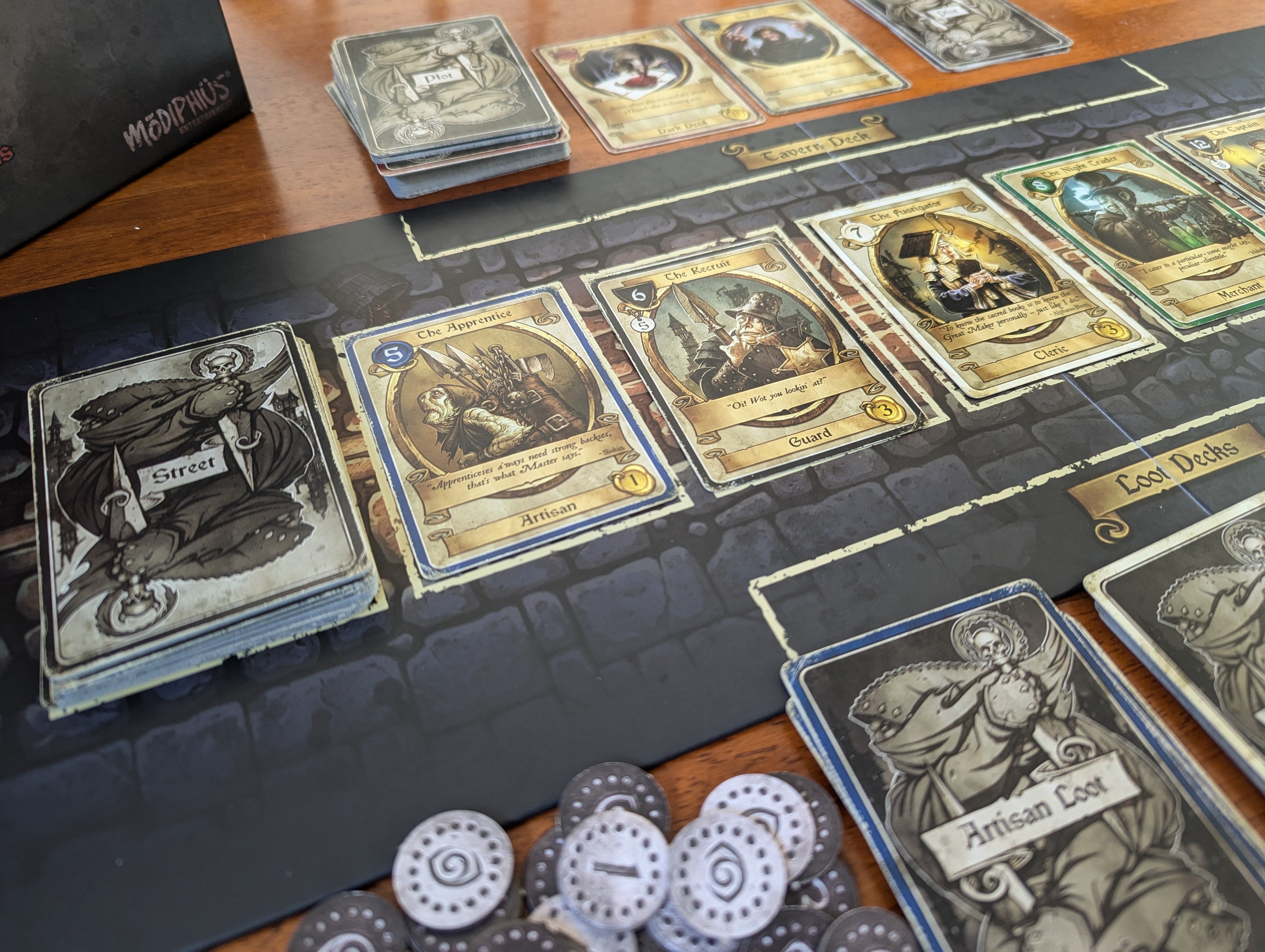 Dark Deeds cards lined up on a black tabletop playing field.